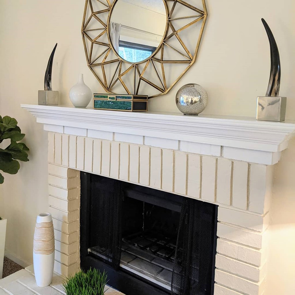 A white fireplace with a mirror above it.