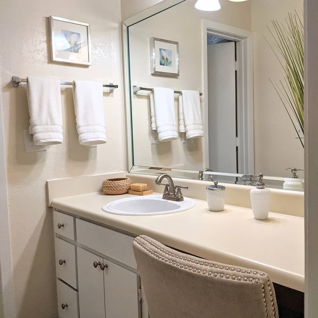 A bathroom with a sink, mirror, and towel rack.