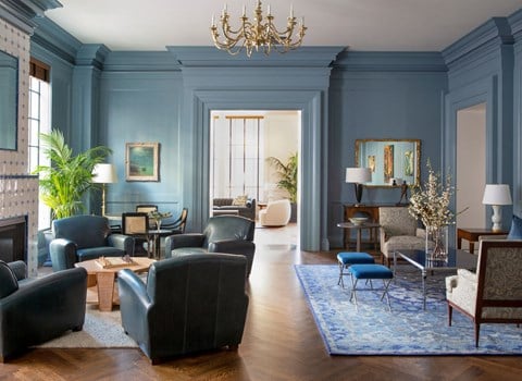 a living room with blue walls and furniture and a chandelier