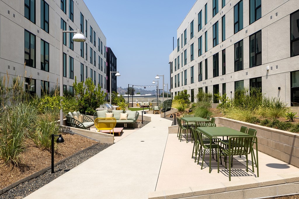 A patio area with tables and chairs is surrounded by buildings.
