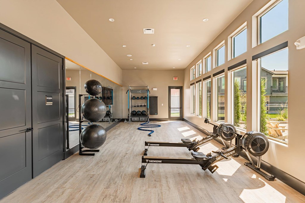 A gym with a row of exercise bikes and a row of dumbbells.