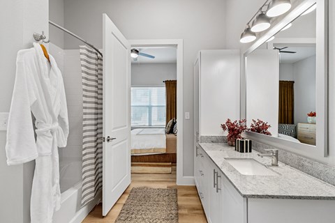 A white bathroom with a white robe hanging on the wall.