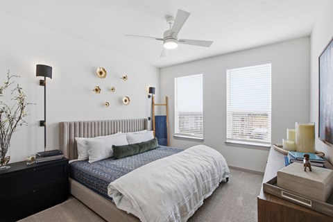 A bedroom with a bed, nightstand, and a ceiling fan.
