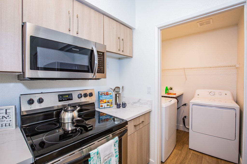 A small kitchen with a stove, microwave, and washing machine.