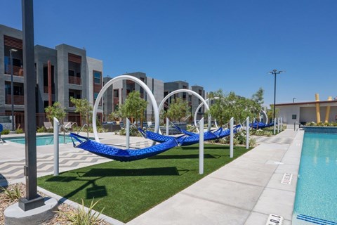 A pool area with hammocks and a clear blue sky.