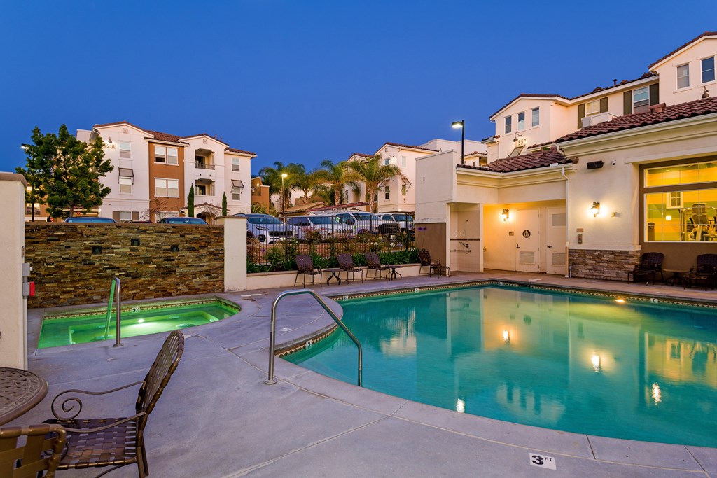 A swimming pool surrounded by chairs and a stone wall.