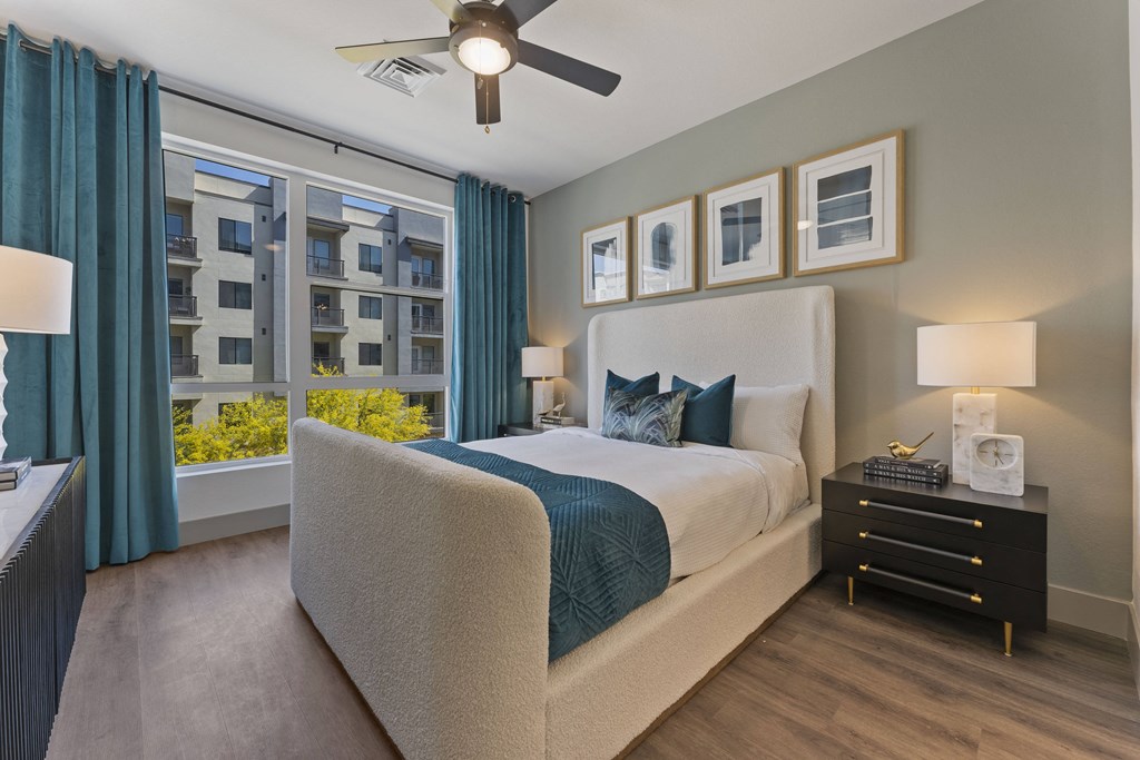 a bedroom with a large window and a bed and a ceiling fan