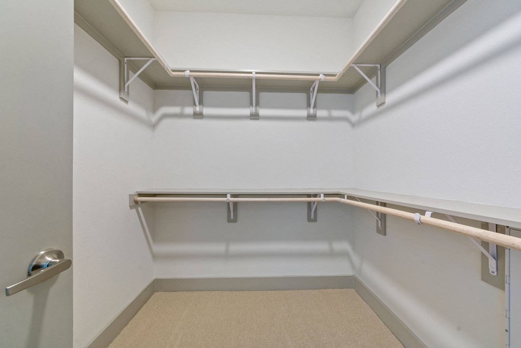 a spacious room with white walls and a closet with empty shelves and rails