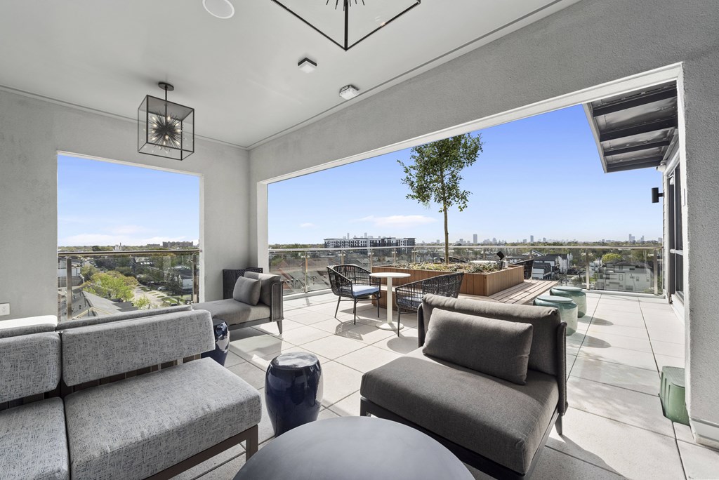 A modern outdoor seating area with grey couches and a view of the city.