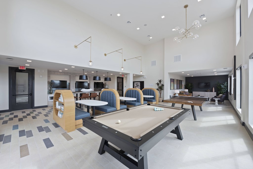 A billiard table is in the middle of a room with blue chairs.