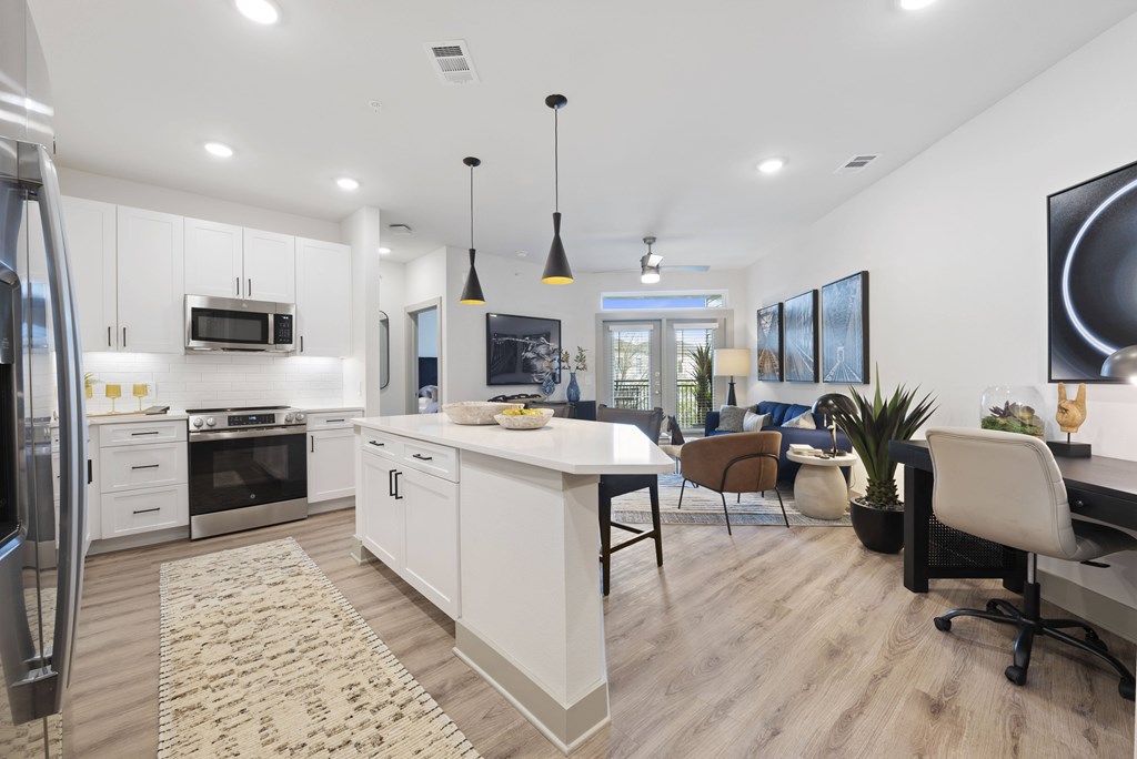 A modern kitchen with white cabinets and a wooden floor.