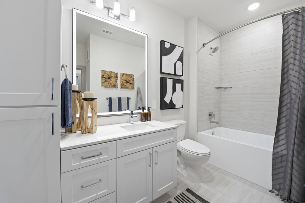 A white bathroom with a toilet, sink, and mirror.