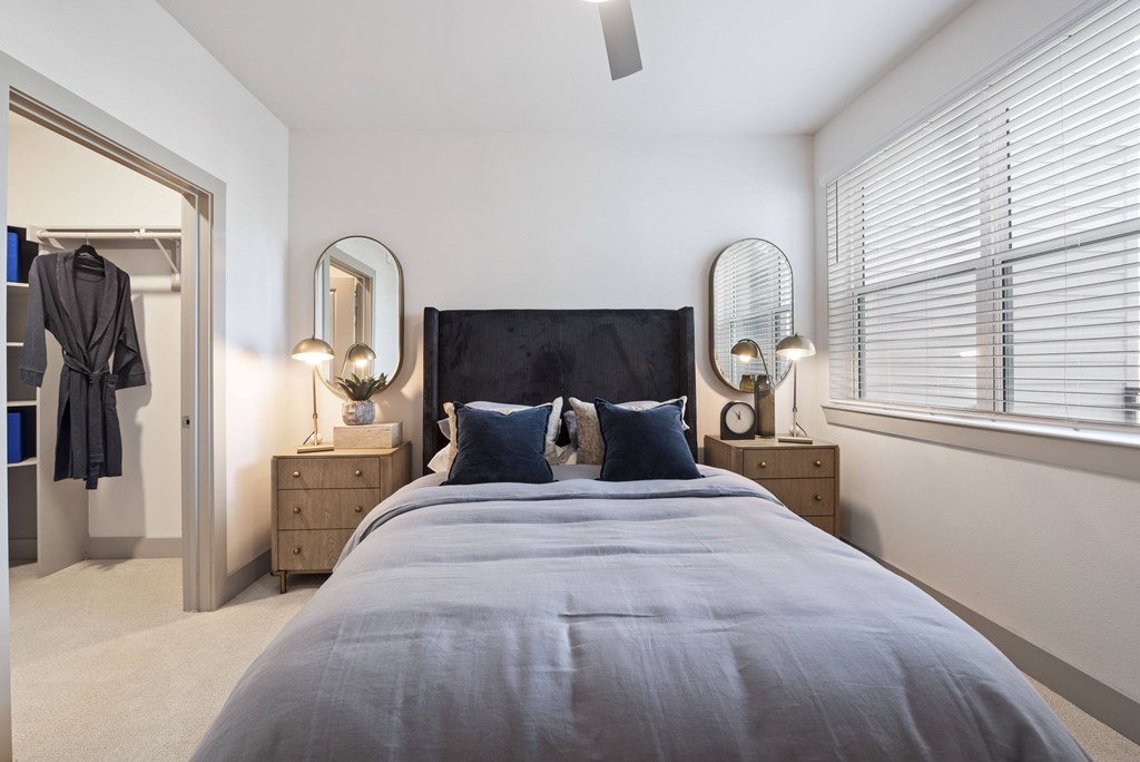 A bedroom with a large bed and two lamps on either side of it.