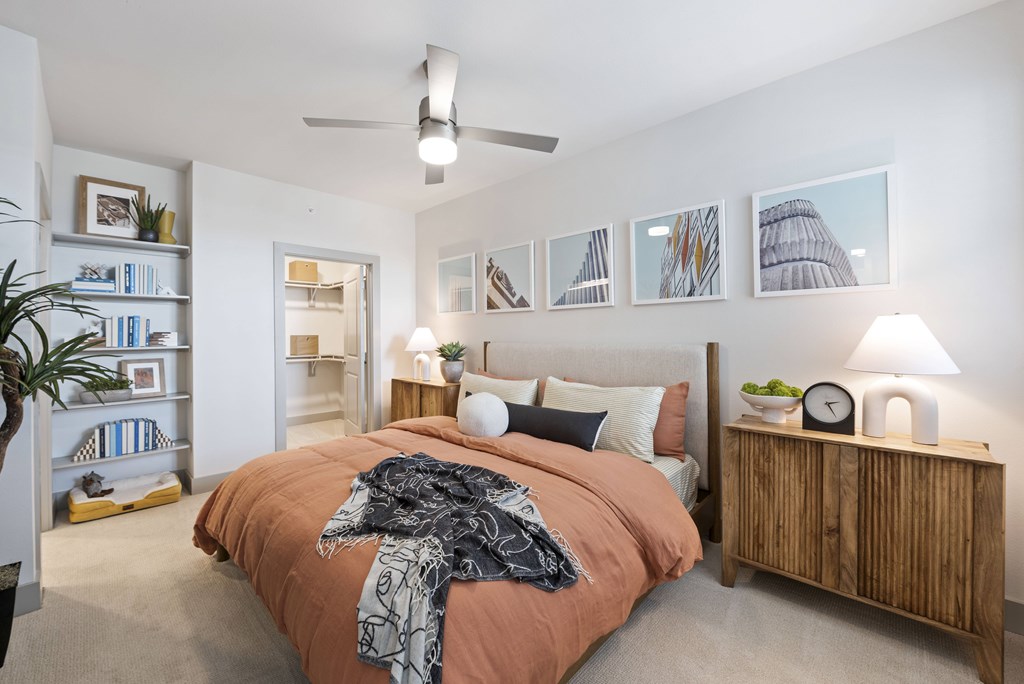 A bedroom with a bed, a ceiling fan, and a bookshelf.