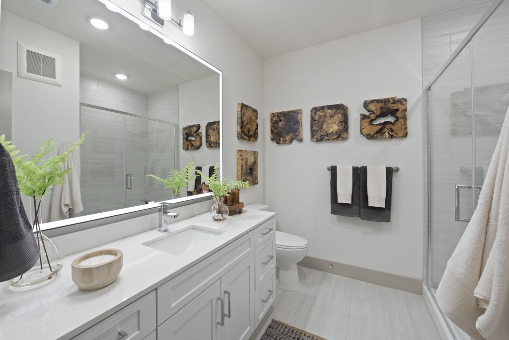 A bathroom with a white counter top and a mirror above it.