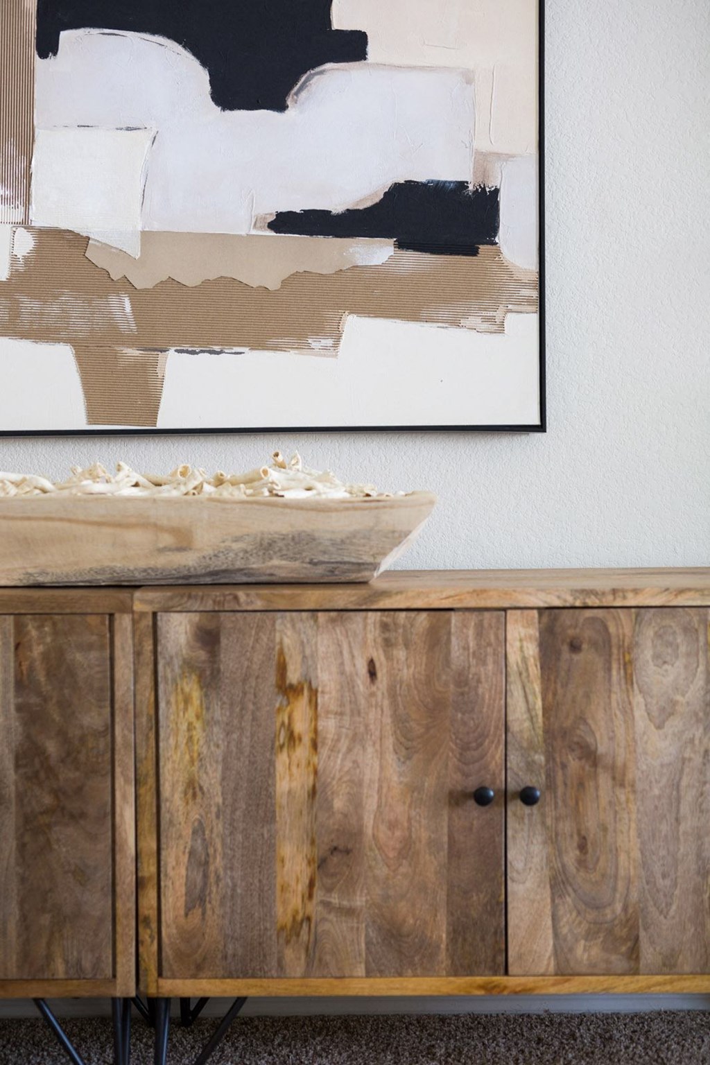 a wooden sideboard with a painting on the wall behind it