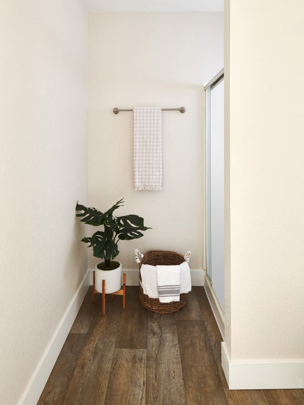 a small bathroom with a wooden floor and a white plant in a white pot
