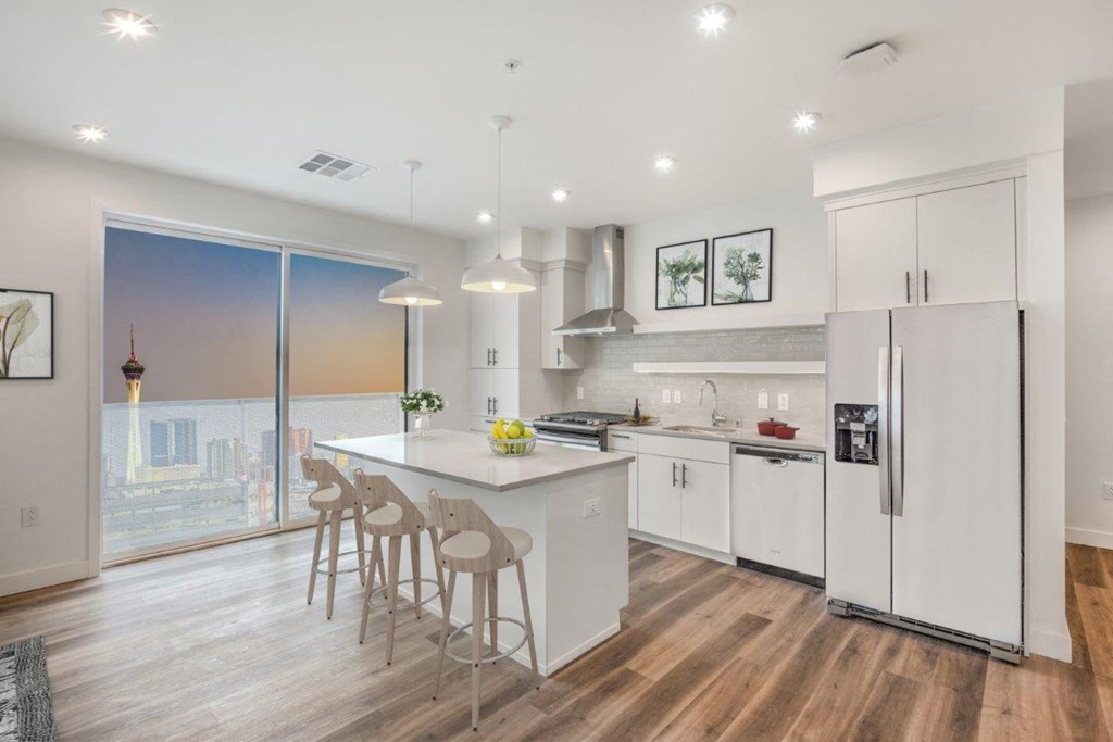 a kitchen with white cabinetry and a white island with three stools