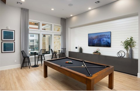a billiards table in a game room with a bar and a tv