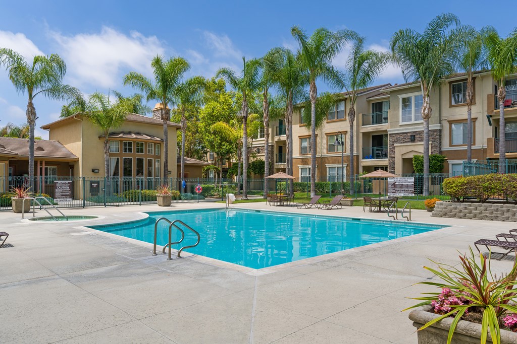 A swimming pool surrounded by palm trees and apartment buildings.