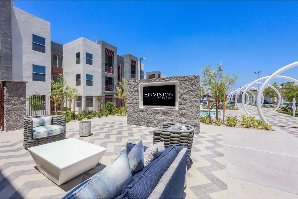 A modern outdoor seating area with a stone sign that reads "ENVISION".