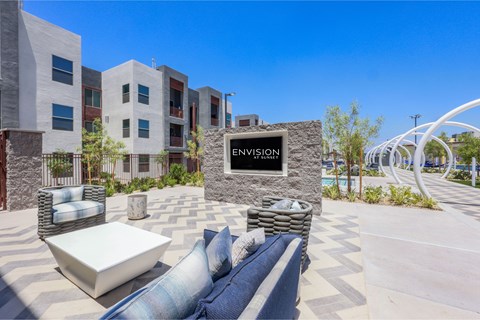 A modern outdoor seating area with a stone sign that reads "ENVISION".