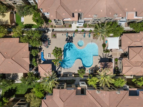 An aerial view of a swimming pool surrounded by houses and trees.
