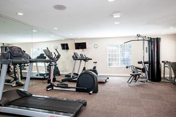 A gym with treadmills, elliptical machines, and other exercise equipment.