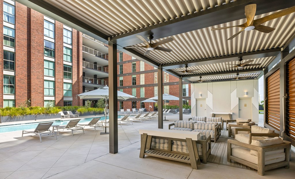 A patio area with a pool, lounge chairs, and a ceiling fan.