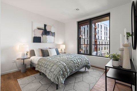 A bedroom with a large bed and a window overlooking a city.