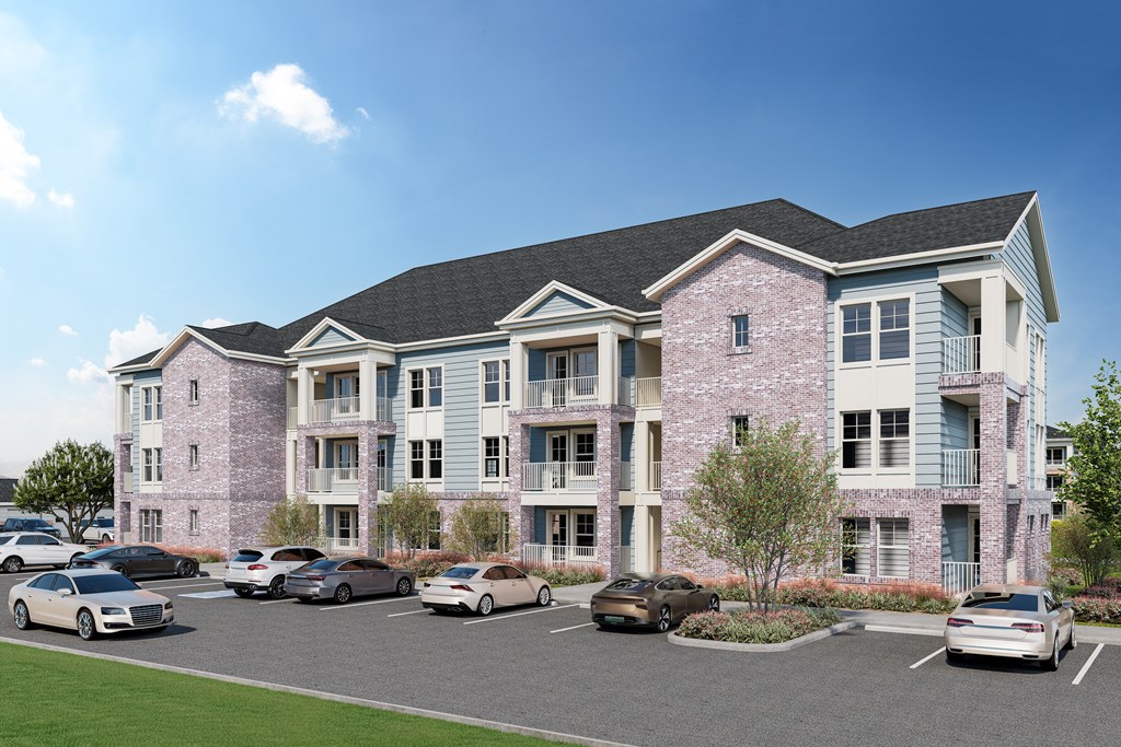 A large pink building with a parking lot in front.