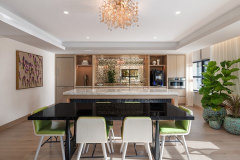 A modern dining room with a black table and green chairs.