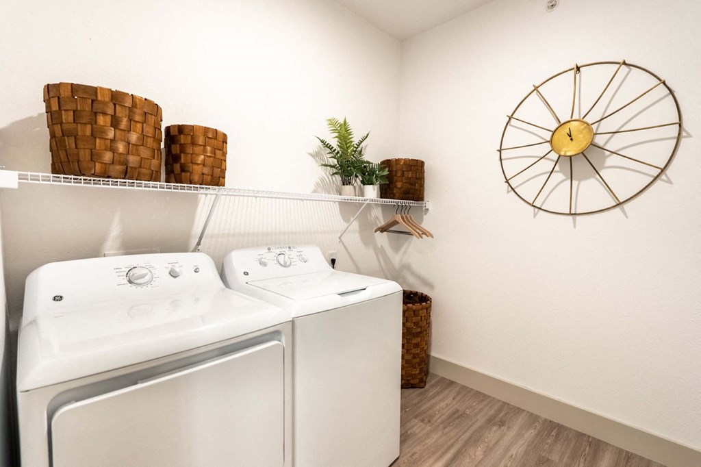 a washer and dryer in a laundry room with a clock on the wall