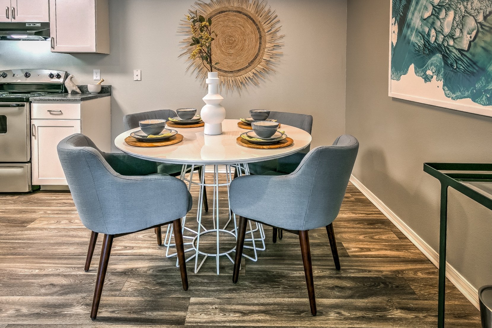 A dining table with four chairs and a decorative plate stand in a kitchen.