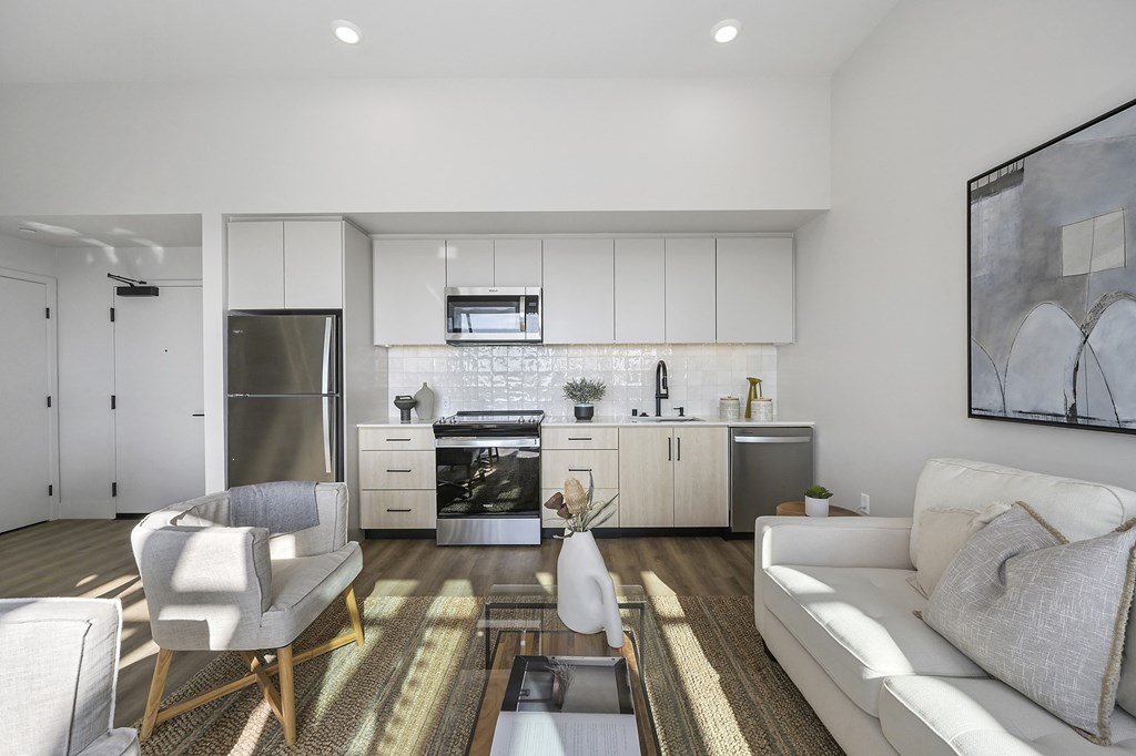 a living room with a white couch and a kitchen with stainless steel appliances