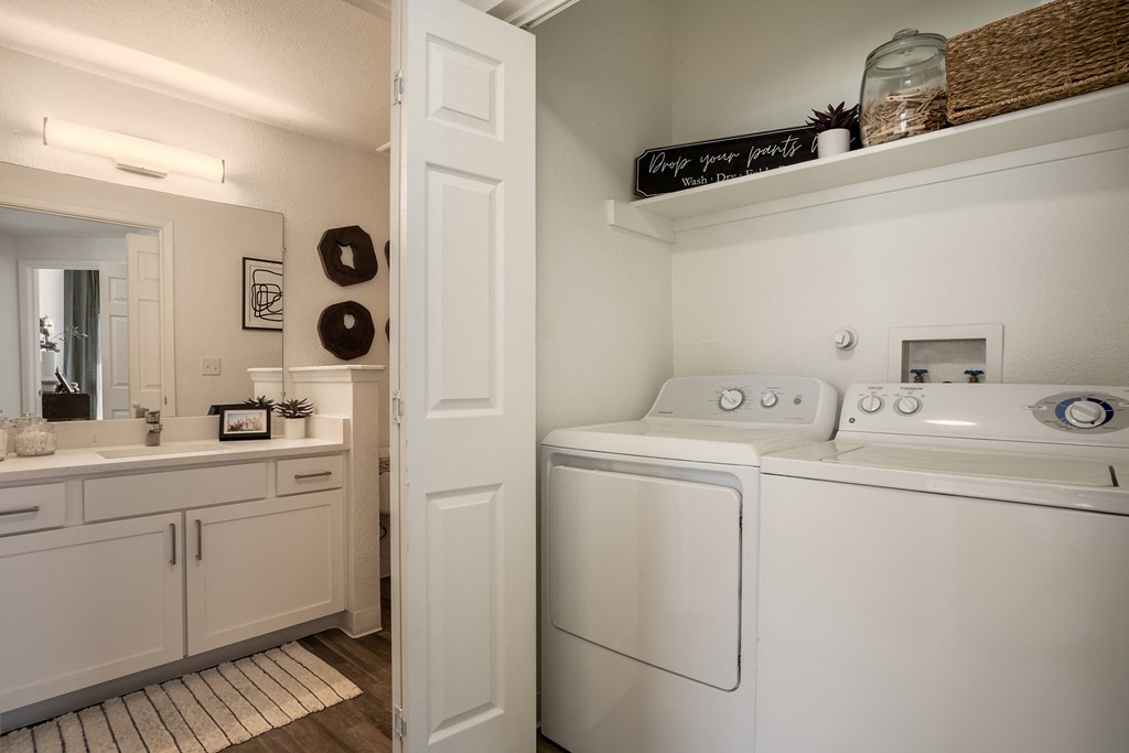 a white washer and dryer in a laundry room with a sink and mirror