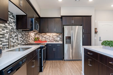 A kitchen with dark brown cabinets and a stainless steel refrigerator.