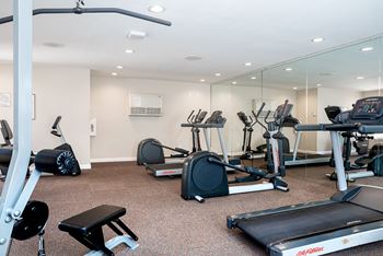 A gym with a variety of equipment including treadmills, weights, and exercise machines.