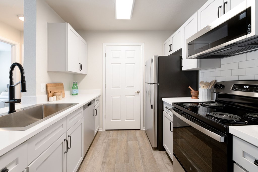 A kitchen with white cabinets and a black stove top oven.
