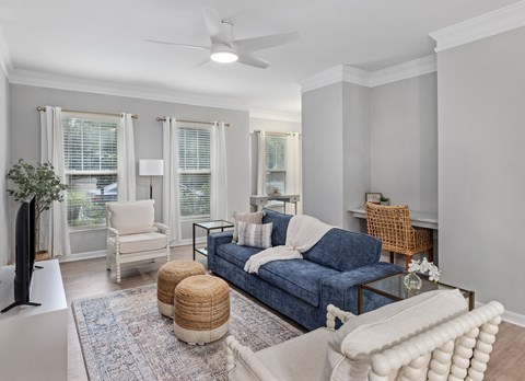 A living room with a blue couch, a white chair, and a white ottoman.