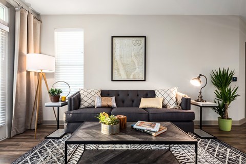 A living room with a grey couch, a coffee table, and a large painting on the wall.