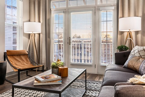 A living room with a chair, a couch, a table, and a window with blinds.