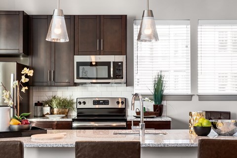 A modern kitchen with dark brown cabinets and a granite countertop.
