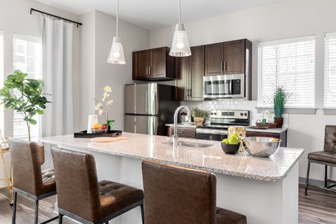 A modern kitchen with brown chairs and a marble countertop.