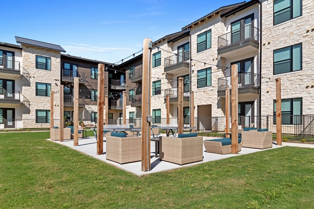 an apartment building with patio furniture and grass