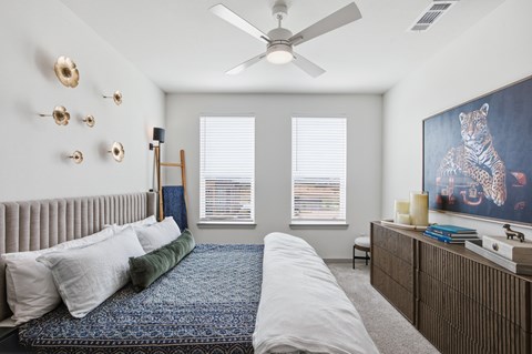 A bedroom with a bed, a dresser, and a painting of a tiger.