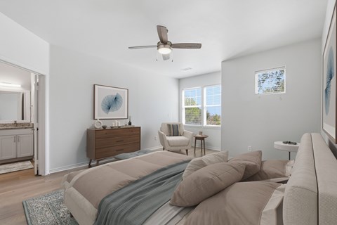 A bedroom with a bed, a dresser, a chair, and a ceiling fan.
