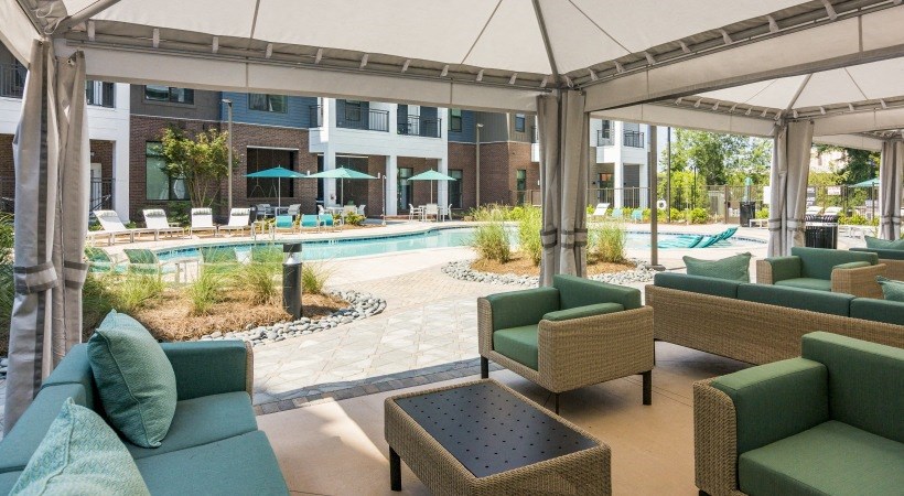 a lobby with couches and chairs and a pool with umbrellas