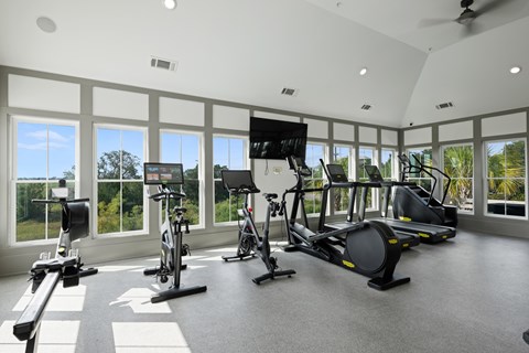A spacious gym with a variety of exercise equipment and a large window overlooking the outdoors.