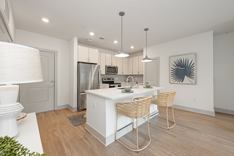 A modern kitchen with white cabinets and a wooden floor.